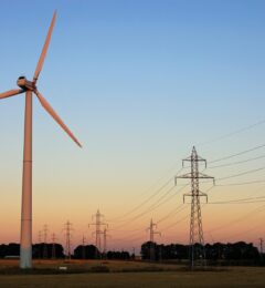 wind-turbine-and-electricity-pylons-against-sky-P6SUP5B